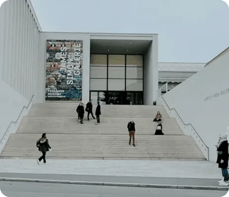 Modern concrete building with wide stairs and people walking, ascending, and sitting.