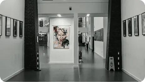 A grayscale art gallery hallway featuring a prominent colorful, expressive portrait painting in the center.